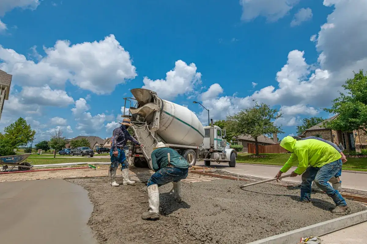 Crew spreading concrete from a mixer truck for a driveway slab in Fort Worth, Texas